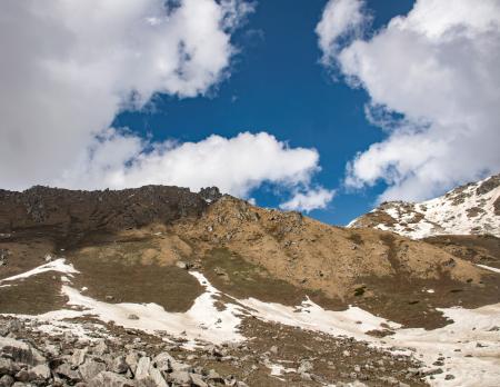 Snow Covered Hill Under Cloudy Sky at Daytime