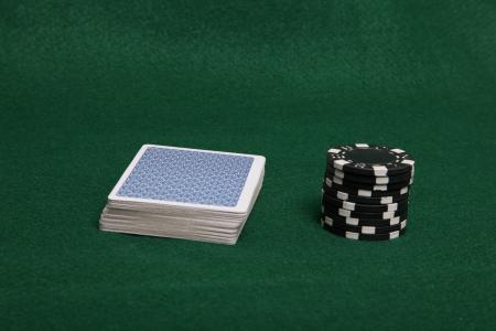 Stack of black poker chips and deck of c