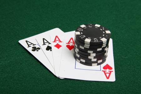 Stack of black poker chips on four aces