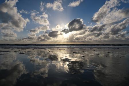 Sun Rays Through Cumulus Clouds Reflecting over Body of Water