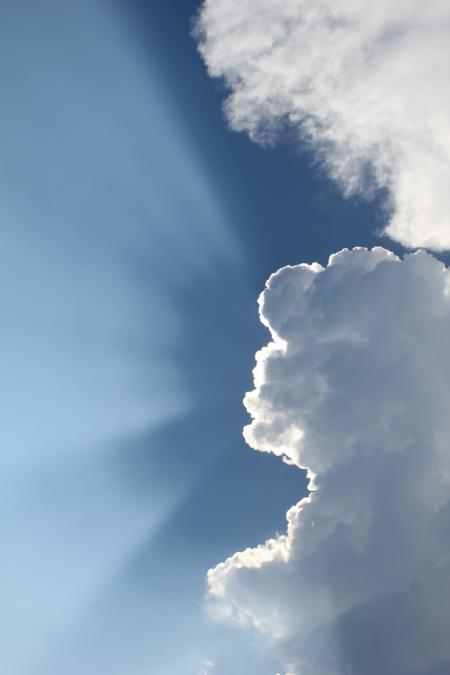 Sun Shining Behind Clouds in Blue Sky