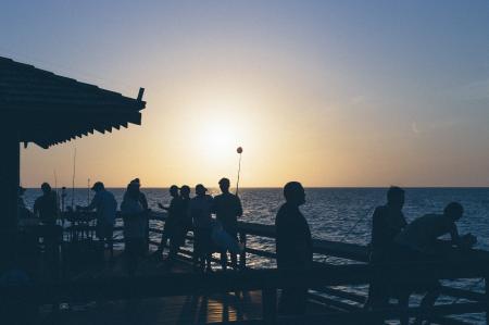 Sunset over Silhouette of People Near Body of Water