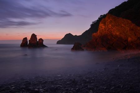 Tall Rock Formation Submerged in Water Near the Shore during Golden Hour