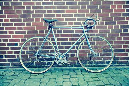 Teal and Black Road Bike Near Black and Brown Brick Wall