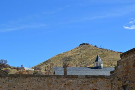 The wall of the fortress with a view of the hill with a cross