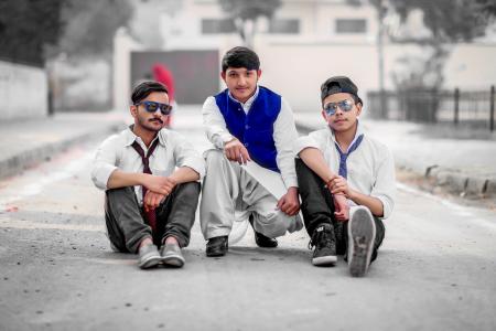 Three Men Sitting on Gray Concrete Road