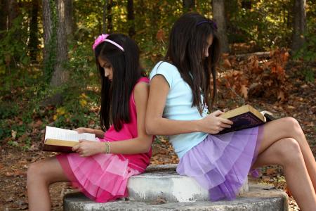 Two cute young girls reading books