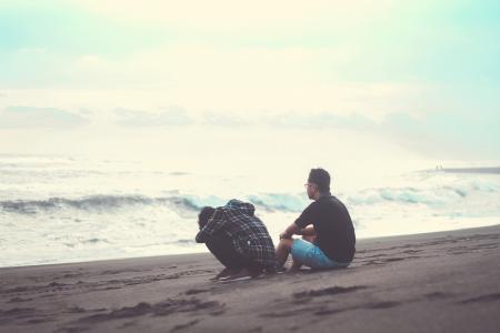 Two Man Sitting on the Sand Near the Beach