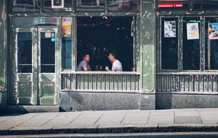 Two Men Eating While Facing Each Other Inside Store