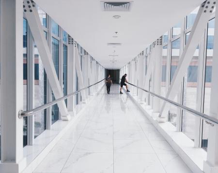 Two People Standing on Hallway Near Glass Window