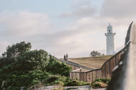 Two Person Standing Near White Lighthouse