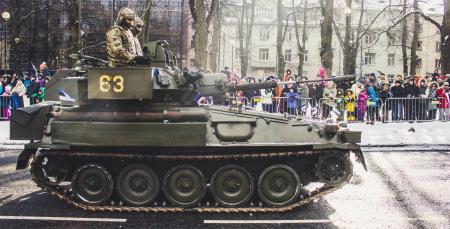 Two Soldiers Ride on Green Military Tank Surrounded With People