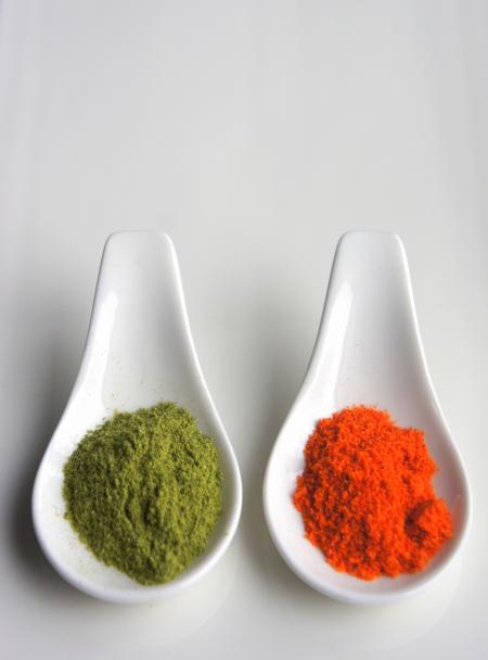 Two White Serving Spoons Filled With Condiments