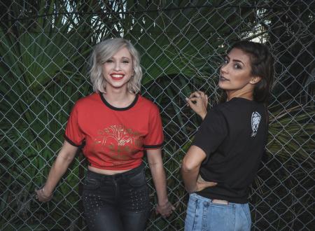 Two Woman in Black and Red Dress Standing Near Fence