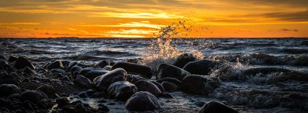 Waves Splashing at Stones on Beach during Sunset