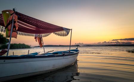 White and Blue Wooden Boat on Body of Water Under Orange Sunset