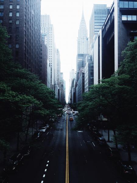 White and Red Car on Black Concrete Narrow Road in Between High Rise Buildings Photograph