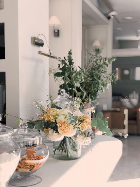 White and Yellow Petaled Flowers Centerpiece Near Clear Glass Jars on Top of White Wooden Table