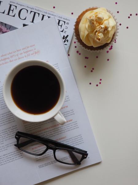 White Ceramic Cup With Coffee on Top of Opened Book and Near Eyeglasses