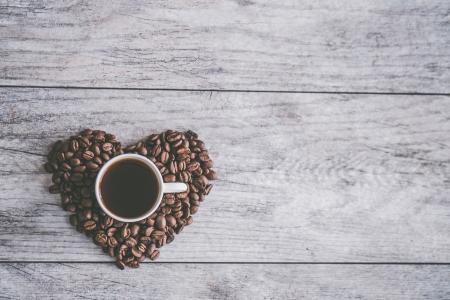 White Ceramic Mug Filled With Brown Liquid on Heart-shaped Coffee Beans