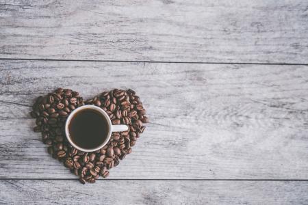 White Ceramic Mug Filled With Brown Liquid on Heart-shaped Coffee Beans
