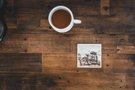 White Ceramic Mug With Coffee Beside Photo of Two Mountain Bikes