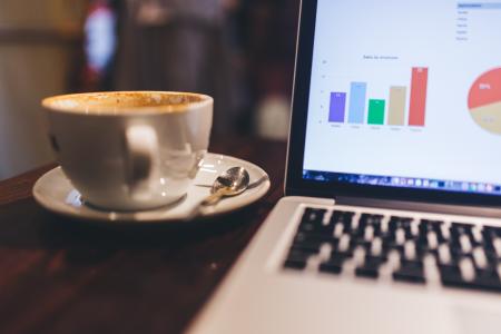 White Ceramic Tea Cup Beside White and Black Laptop Computer