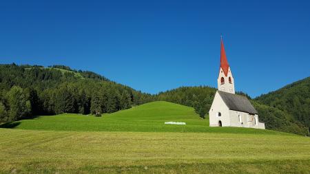 White Gray and Red Chapel on Green Field during Clear Sky Day Time