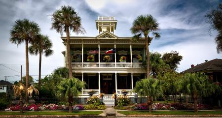 White Painted Structure With Green Palm Trees in the Front