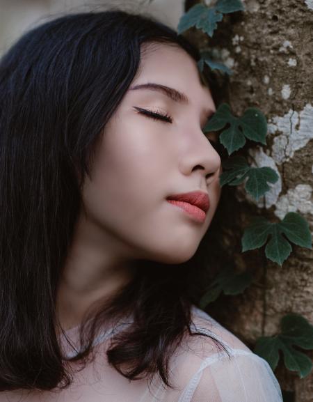 Woman Closing Her Eyes Beside Green Vine Plant