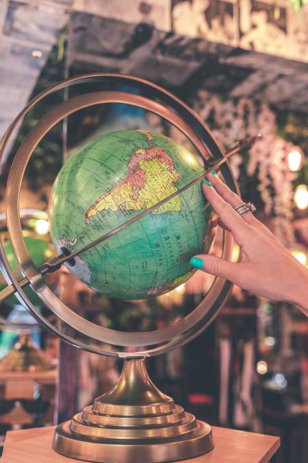 Woman Hand Touches Green Desk Globe