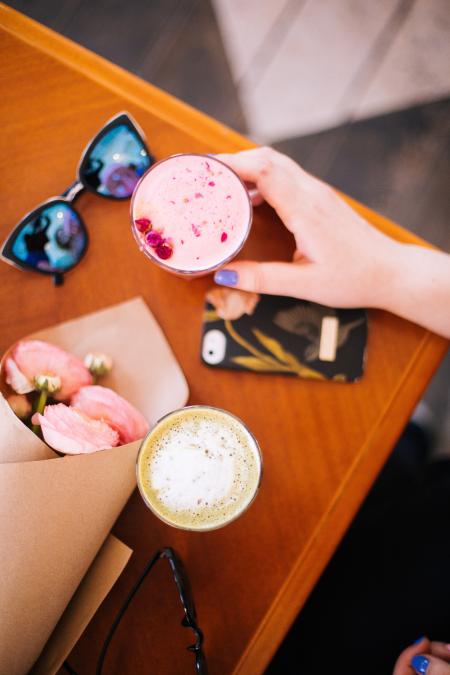 Woman Holding Beverage Filled Cup Near Sunglasses and Phone