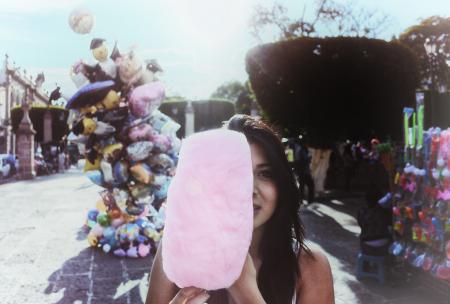 Woman Holding Cotton Candy With Balloons in Background
