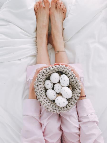 Woman Holding Gray Crochet Bowl With Seven Painted Eggs