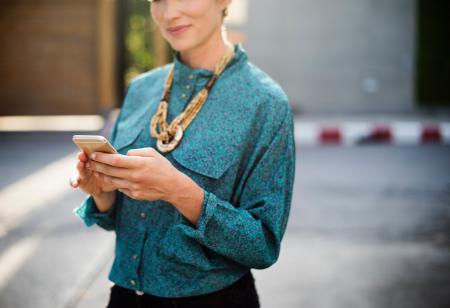 Woman Holding Iphone Wearing Long-sleeved Shirt And Gold Necklace