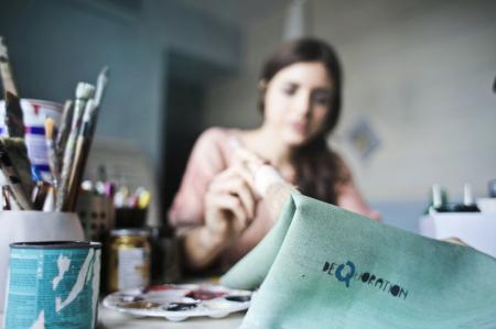 Woman Holding Paper Near Paint Brushes