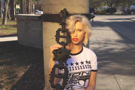 Woman Holding Shackles Leaning on Concrete Post