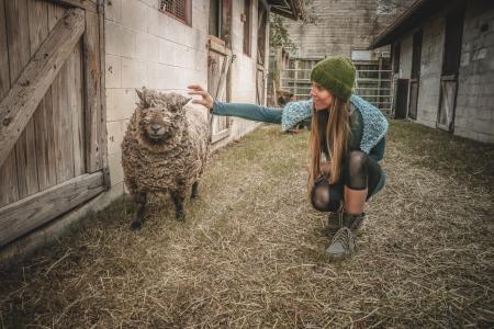 Woman Holding Sheep Beside Wall