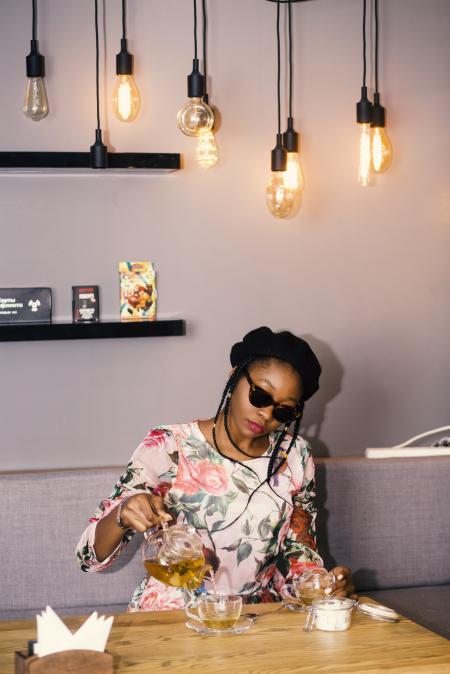 Woman Holding Teapot Near Table