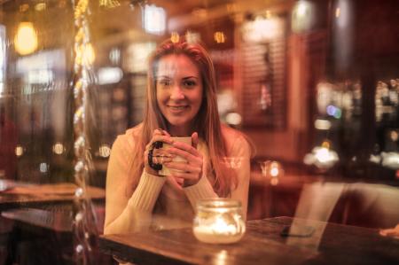 Woman Holding White Ceramic Cup Sitting Near Brown Wooden Table