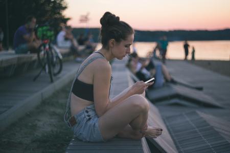 Woman in Black and Gray Shirt Sitting Near Ocean at Sunset