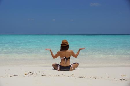 Woman in Black and White Bikini Sitting on White Stand Facing Beach during Daytime