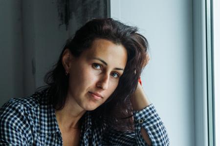 Woman in Black and White Gingham Long-sleeved Top Holding Her Hair Beside White Surface