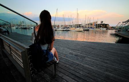 Woman in Black and White Stripe Scoop Neck Shirt Sitting on Brown Wooden Bench in Ship Dock during Daytime