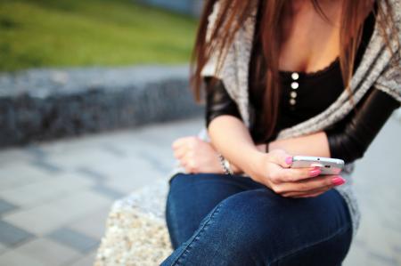 Woman in Black Elbow Sleeve Shirt and Blue Denim Jeans Sitting on the Grey Rock during Daytime