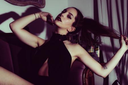 Woman in Black Halter-neck Top Lying on Purple Suede Padded Couch With Brown Wooden Frame