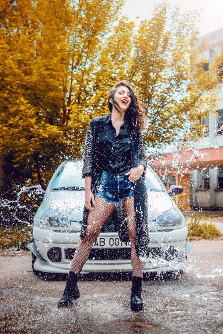 Woman in Black Long-sleeved Top and Blue Denim Shorts Standing in Front of Car