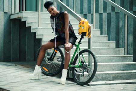 Woman in Black Sleeveless Dress Sitting on Green Bike