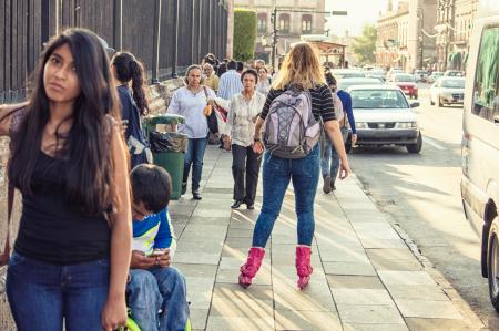 Woman in Black T-shirt, Blue Washed Denim Jeans and Pair of Pink Inline Skates Skating in Street