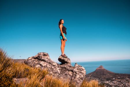 Woman in Black Top and Blue Shorts on Stone Under Blue Sky